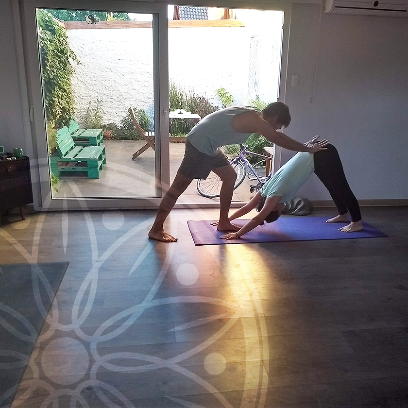 Instructor ayudando a alumna a hacer una posición de yoga